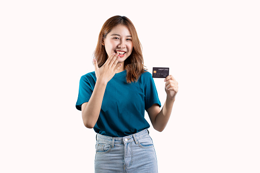 Portrait of Asian woman in blue denim shirt holding credit card and smiling isolated on white background looking at camera the concept of feeling happy