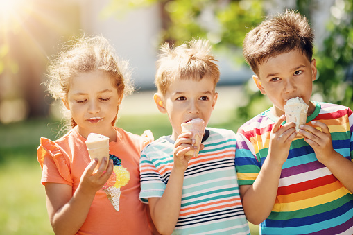 Group of children in the park eating cold ice cream. Concept of friendship and family relationship.