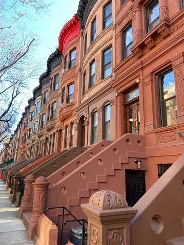 A row of Harlem brownstone houses with stoops and colorful cornices