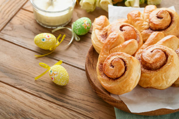 istock Easter breakfast Holliday concept. Easter bunny buns rolls with cinnamon made from yeast dough with orange glaze, easter decorations, colored eggs on old wooden background. Easter Holliday card. 1465585461
