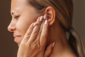 Young caucasian blonde woman holding her ears with her hands. Pain and tinnitus, ear otitis