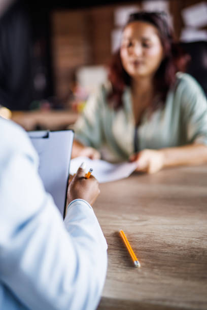 Woman holding a clipboard and writing notes while interviewing a candidate for a job stock photo
