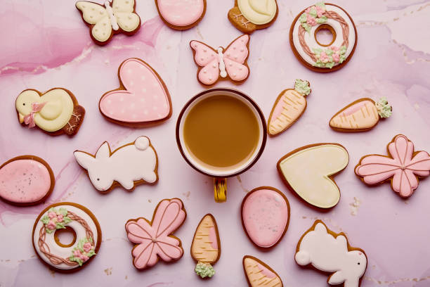 パステルイースター背景 – クッキーの中のコーヒーカップ。ピンクの背景にイースターの艶をかけられたシンボルを持つ春のカード。