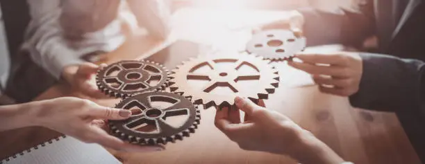 Group of people working in the office while putting together cogwheels. Concept of teamwork and togetherness.