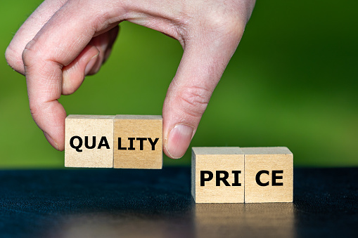 Symbol for selecting a product with a high quality insread of a low price. Wooden cubes form the words quality and price.