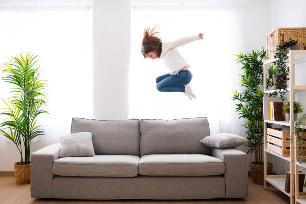 ソファに飛び乗る小さな女の子 - domestic life jumping child sofa ストックフォトと画像