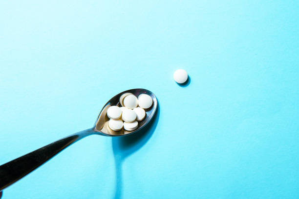 istock Dietary supplements. White vitamin tablets on iron spoon on a blue background 1465591930