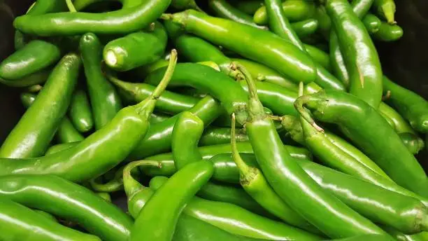 collection of green chilies in basket in supermarket