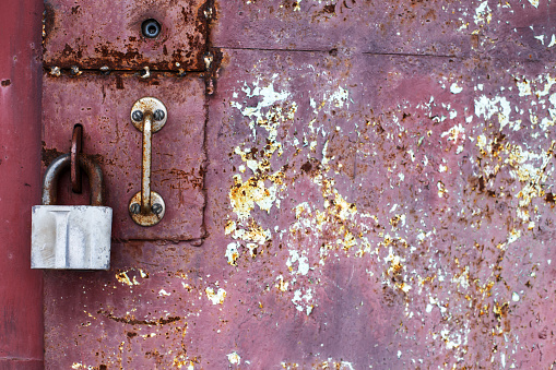 lock on an old metal rusty door. abstract background. Texture of an old grunge metal plate with cracked paint.
