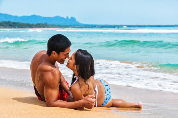 Swimming in clothes. Portrait of a beautiful man and woman wet in sea. Couple hugging and kissing in sea. Male kisses and hugs female standing on water with big waves ocean and enjoying a summer day.