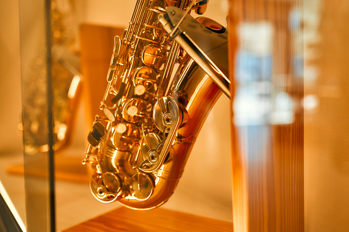 Buying a saxophone from a musical instrument store. A shiny gold saxophone on a display shelf. Hobbies and recreation.