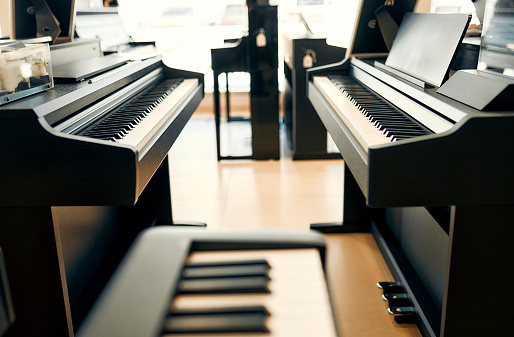 Close-up of black piano keys in a musical instrument store. Lots of different keyboard instruments for sale. Hobbies and recreation.