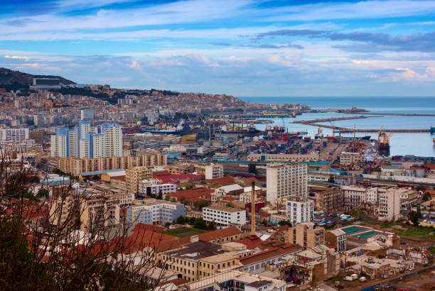 View of the city, harbour and port district of Algiers, the capital city of Algiers. Beautiful blue sky with some clouds, viewed from on top of the hill and looking down on the central parts of the city. Harbour is in the distance.