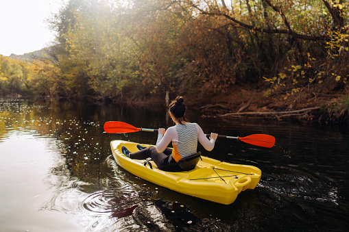 Photo of a beautiful woman kayaking on down the river on a beautiful autumn day