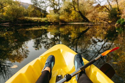 Photo of human feet, kayaking on down the river on a beautiful autumn day