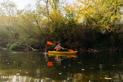 Photo of a beautiful woman kayaking on down the river on a beautiful autumn day