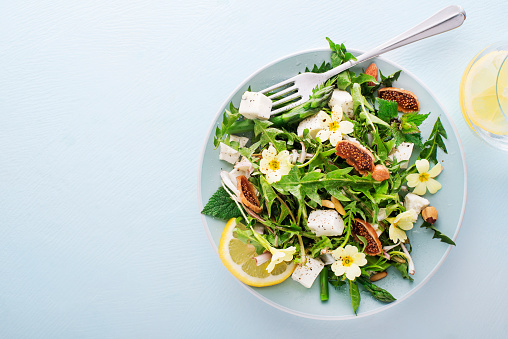 Spring salad with dandelion, asparagus, wild garlic, flowers, nettle and cream cheese. Healthy ingredients for spring detox