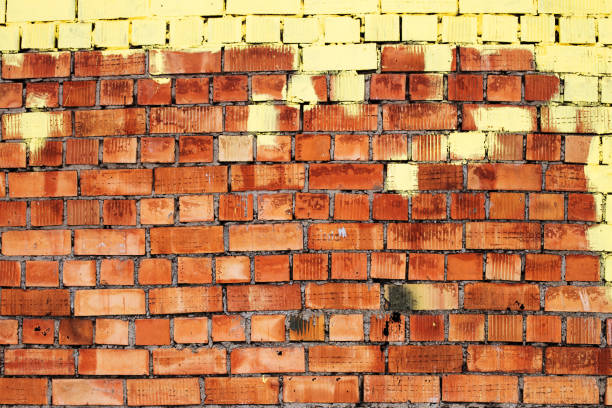 Red grunge brick wall, abstract background texture with old vintage style pattern with yellow paint on top.