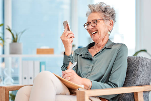istock Senior, business and woman on mobile video call while writing notes and brainstorming for ideas with vision. Inspiration, cellphone video conference and mature female ceo planning in a notebook 1465603606