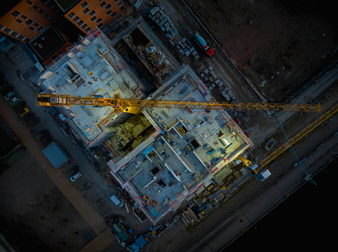 Aerial view of construction site with crane and building. Top down view of construction site with crane and concrete mixer truck.