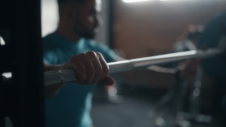 SLO MO A muscular man lifts a barbell from a rack