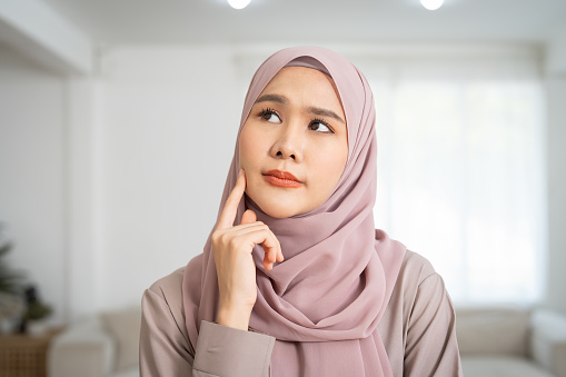 Close up of Asian young muslim woman wear hijab headscarf standing and positive thinking at home
