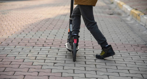 istock Teenager rides a scooter on a brick road 1465607847