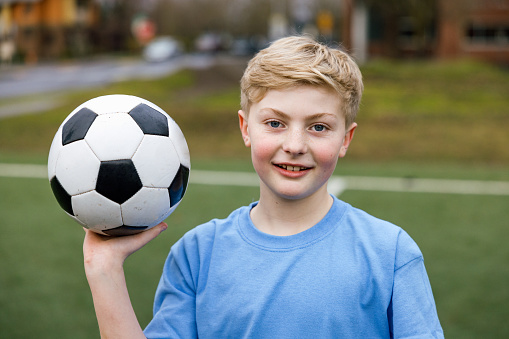 A confident Caucasian male soccer player stands for a portrait at a team practice game.