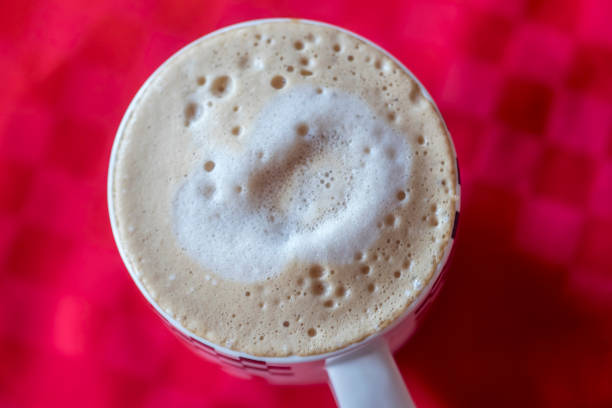 a cup of coffee, a cup on a red background a cup of coffee, a cup on a red background milk froth stock pictures, royalty-free photos & images