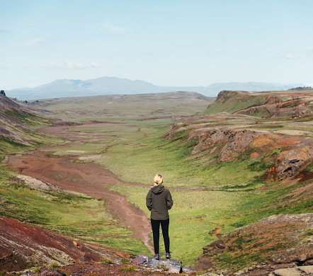 Woman standing on top of the hill enjoying the view on dramatic and colorful volcanic landscape in Iceland (Dyradalur).