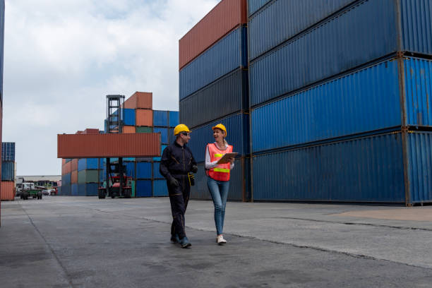 istock Industrial worker works with co-worker at overseas shipping container yard . Logistics supply chain management and international goods export concept . 1465613798
