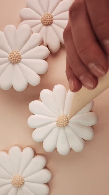 Icing cookies in the shape of a daisy flower.