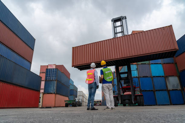 istock Industrial worker works with co-worker at overseas shipping container yard . Logistics supply chain management and international goods export concept . 1465615884
