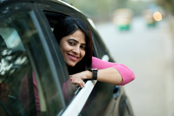 Smiling thoughtful woman looking outside from a moving car