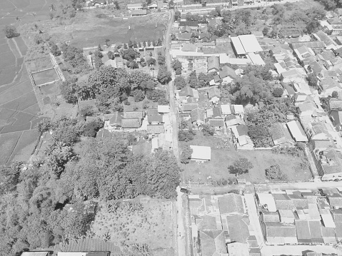 Black and white photo of a village road that divides housing in the Cikancung area - Indonesia.