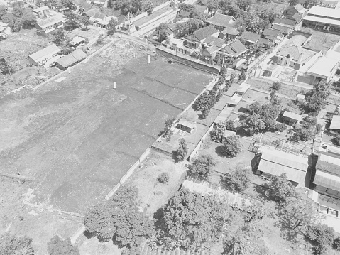 Black and white photo of an aerial view of a rice field in the middle of a village settlement in the Cikancung area - Indonesia.