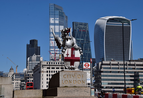 London, UK - April 23 2021: A dragon boundary mark and the City of London, the capital's financial district, view on London Bridge.