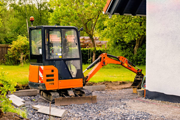 A small orange portable excavator bulldozer in the vicinity of a private home. stock photo