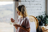 A Happy Beautiful Blonde Woman In Pajamas Looking Away While Eating Breakfast In The Morning