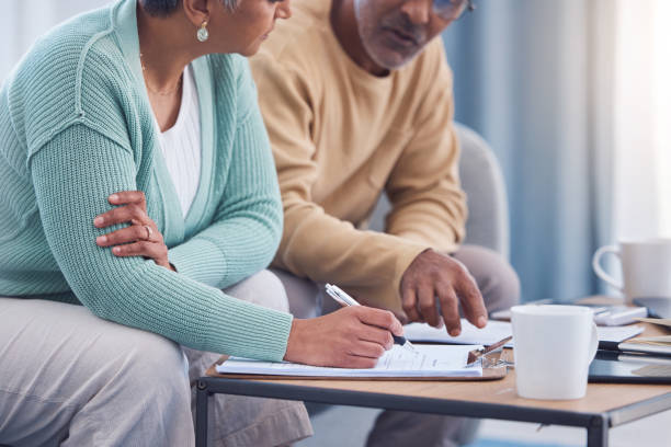 Senior couple, documents and sign contract for life insurance or home mortgage. Discussion, signature and retired elderly man and woman signing legal paperwork for will or loan application together. stock photo