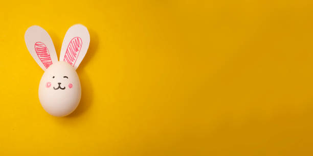 istock Easter greeting card. Chicken egg with hare ears on yellow background 1465622050