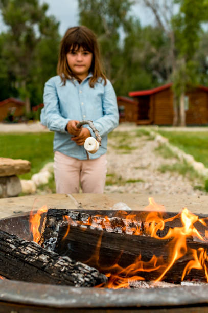 istock Cute kid roasts marshmallows making s’mores over a campifire 1465625051