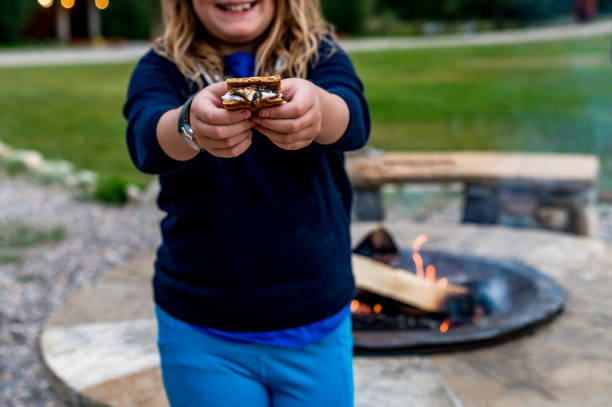 istock Cute kid roasts marshmallows making s’mores over a campifire 1465625203
