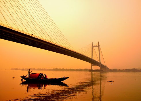 A sunset scene on river Ganges/Ganga/Hooghly, as seen from Prinsep ghat in Kolkata, the capital of West Bengal. The Vidyasagar Setu (bridge) can be seen in the background.