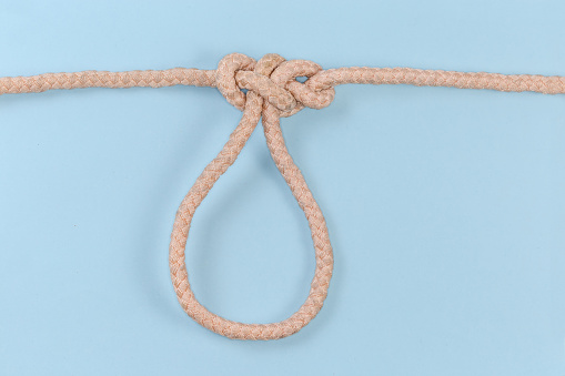 Tightened rope knot Span loop tied with a climbing rope on a blue background