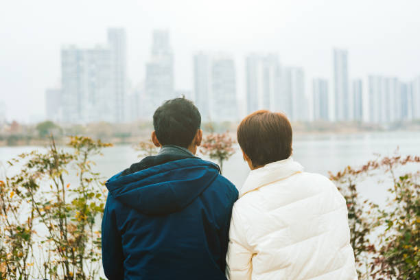 Rear view of middle-aged and elderly couples sitting on benches, looking towards the distant scenery