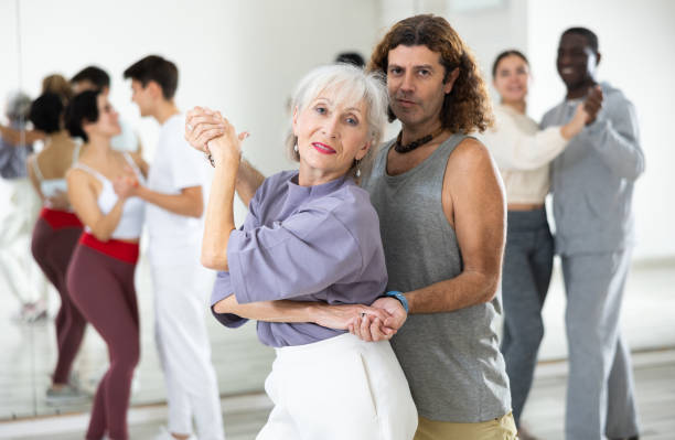istock Happy caucasian guy and old lady practising paired latin dance in dance studio 1465631630