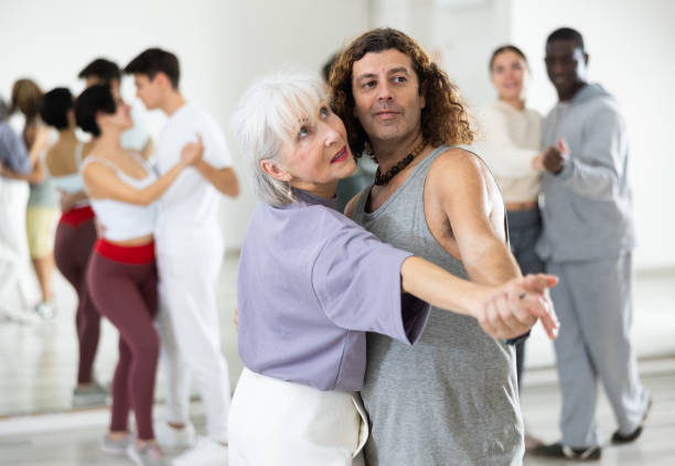 istock Happy caucasian guy and old lady practising paired latin dance in dance studio 1465631651