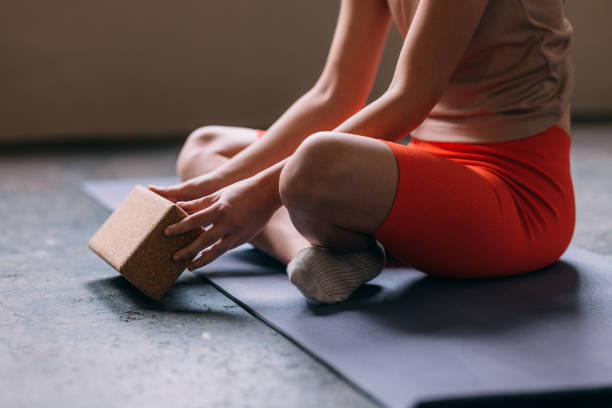 An Unrecognizable Sportswoman Doing Yoga Using A Wooden Brick