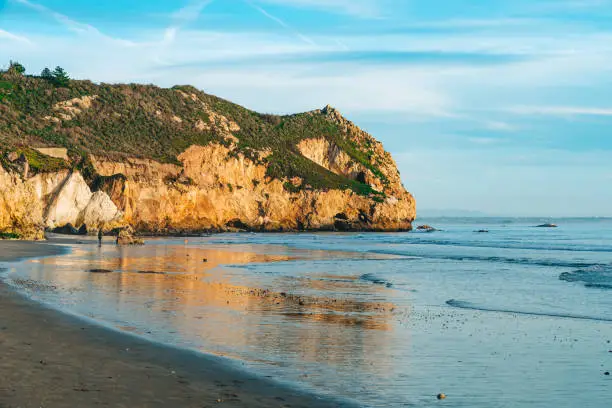 Photo of Avila Beach rocky cliffs at sunset, and ocean view with beautiful cloudy sky in the background, Central Coast of California